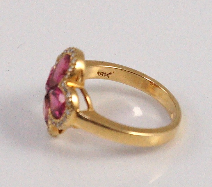 A modern 18k gold four stone pear shaped pink tourmaline set dress ring with diamond chip set border